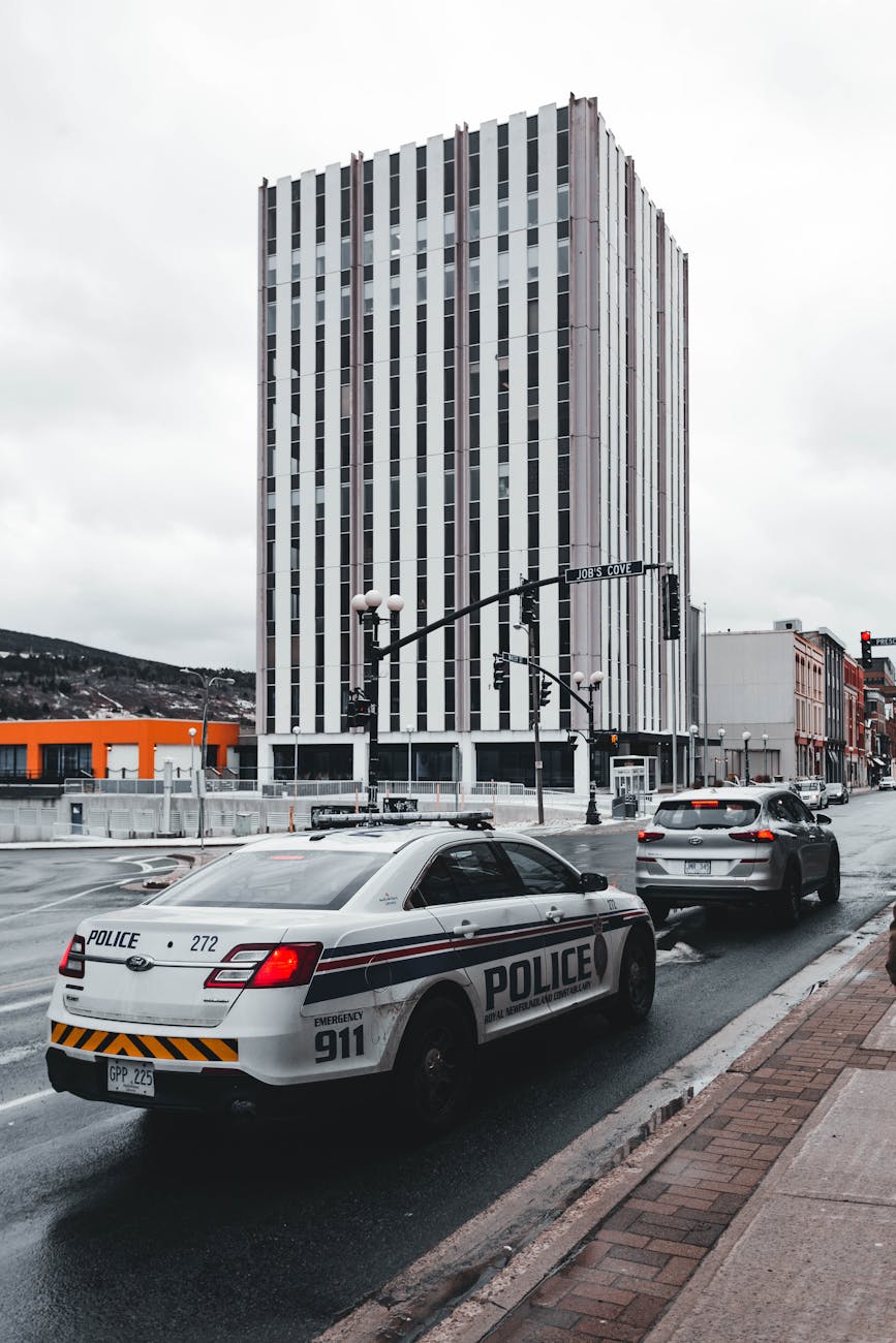 a police car on the road near a high rise building